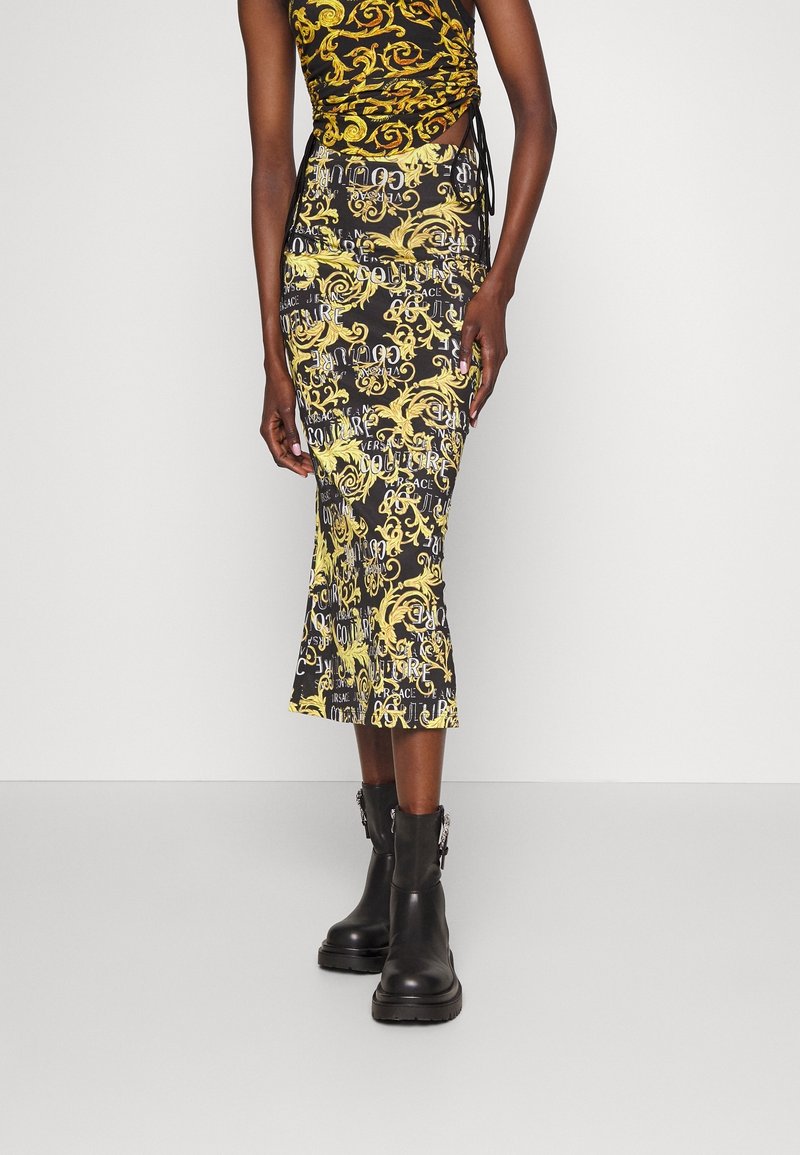 Svart och gul mönstrad midikjol med virvlar och text, med utsvängd fåll och kombinerad med svarta klumpiga stövlar.