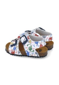Sandalias blancas con patrones coloridos de dinosaurios y confeti, dos tiras ajustables en color azul marino, plantilla de corcho y suela de goma negra texturizada.