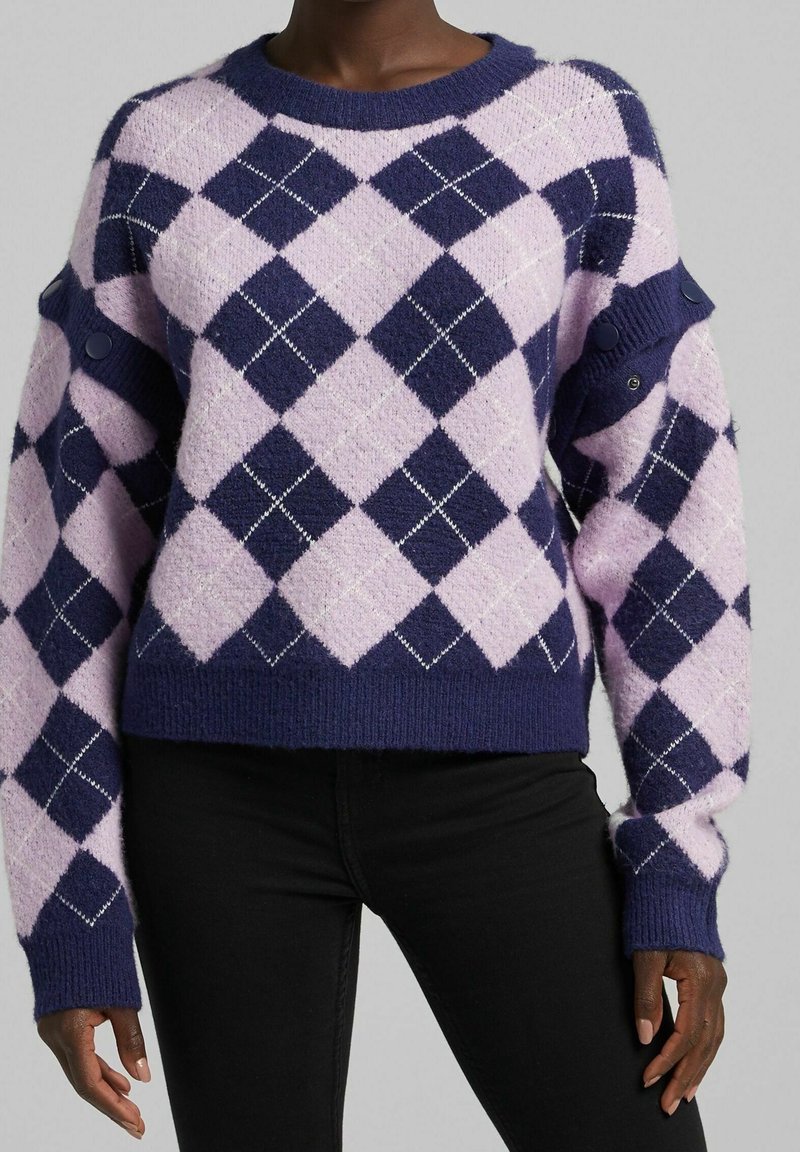 Stickad tröja med ett stort diamantmönster i lavendel och marinblått, accentuerad med vit söm. Fitted muddar och rund halsringning.