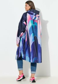 Wasserfester, übergroßer Regenmantel in Marineblau mit bunten abstrakten Mustern. Verfügt über eine Kapuze mit Kordelzug und eine Druckknopfverschluss.