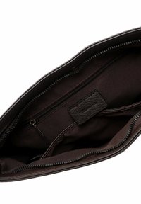 Interno di una borsa a mano in pelle marrone con scomparti con zip, fodera in tessuto liscio e un'etichetta. Chiusura con zip lungo la parte superiore.