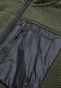 Fleece jacket with a textured olive green body and smooth black nylon accents. Includes a zipper pocket and embroidered logo detail.
