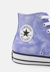 Sneaker Converse All Star alto viola con lacci bianchi, patch del logo a stella nera e suola di gomma bianca con striscia nera.