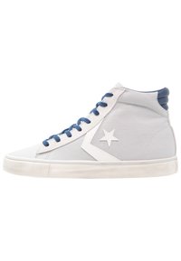 Vysoké tenisky šedé barvy z plátna s bílým hvězdicovým logem a bílou gumovou podrážkou. Obsahují modré tkaničky a texturované šedé detaily na kotníku.