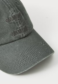 Gray denim cap with embroidered "SAM" on the front. Features a curved brim and visible stitching along the edge.
