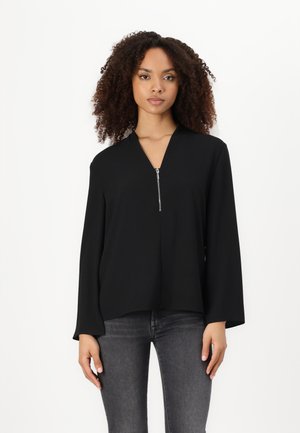 Black long-sleeve top with a V-neck and zippered front detail. Made of smooth fabric, has a loose fit and falls just below the waist.