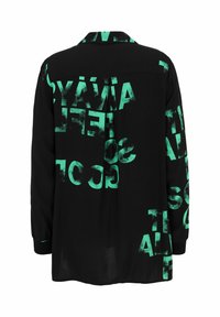 Schwarzes Shirt mit langen Ärmeln, mit auffälligem, unregelmäßigem grünen Grafiktext auf dem Rücken. Aus leichtem Stoff mit Kragen gefertigt.