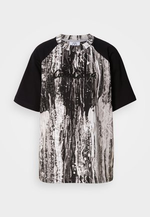 Schwarz-weißes übergroßes T-Shirt mit einem gestreiften abstrakten Muster, kurzen Raglanärmeln und einem gerippten Rundhalsausschnitt.