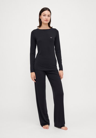 Maglietta nera a maniche lunghe e pantaloni abbinati realizzati in tessuto morbido. La maglietta ha un collo tondo e un piccolo logo sul petto; i pantaloni sono a gamba dritta.