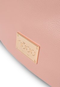 Borsa in finta pelle testurizzata rosa con una placca in metallo dorato con lettering inciso. Superficie liscia con una leggera lucentezza.