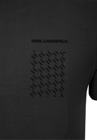 Schwarzes Baumwoll-T-Shirt mit erhabenem schwarzem Logo "KARL LAGERFELD" und einem strukturierten Hahnentrittmuster auf der Vorderseite. Kurzärmlig, runder Hals.