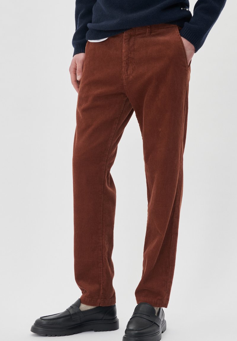 Pantaloni din corduroy maro cu dungi verticale, având o croială dreaptă, buzunare laterale, asortați cu mocasini negri.