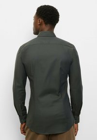 Dunkelgrünes Langarmhemd mit strukturiertem Muster, Knopfmanschetten und tailliertem Schnitt, ausgestattet mit einem klassischen Kragen und glattem Stoff.