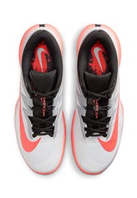Ein Paar weiße und korallenfarbene Nike Vapor Pro Turnschuhe mit schwarzen Schnürsenkeln, roten Innensohlen mit dem Nike-Logo, von oben betrachtet.
