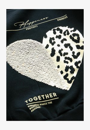 Juodas džemperis su didžiuliu širdies dizainu, padalintu į blizgančią sequinų dalį ir leopardų rašto dalį, su tekstu viršuje ir žemiau.