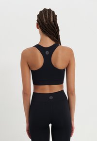 Black athletic crop top with a racerback design, made from a smooth fabric. Features a logo detail on the back and a fitted silhouette.