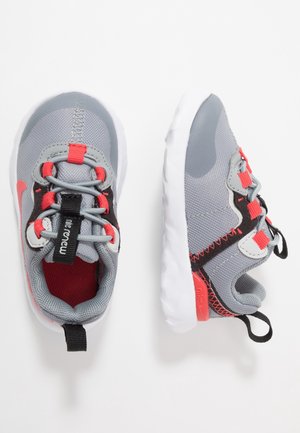 Par af grå og røde småbørns-sneakers med hvide såler, elastiske snørebånd og sorte trækflapper på hvid baggrund.