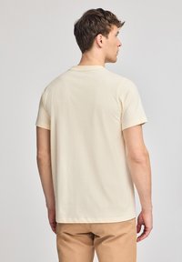 Beige, t-shirt met korte mouwen gemaakt van katoen; heeft een eenvoudige ronde halslijn en een rechte zoom, met een gladde textuur en zonder patronen.