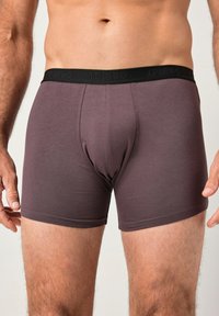 Boxer ajustados para hombres en mezcla de algodón de color mauve oscuro, con una cinturilla elástica negra con marca grabada, textura suave y diseño ceñido.