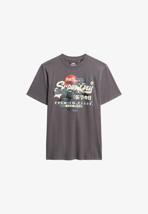 Grijze katoenen t-shirt met een grafische print van bergen en een zon, met "Superdry" tekst in wit en zwart. Korte mouwen en ronde hals.