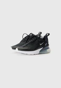 Sapatilhas desportivas pretas com um cabedal texturizado, apresentando uma sola branca e amortecimento de ar visível. Inclui atacadores pretos e detalhes de marca.