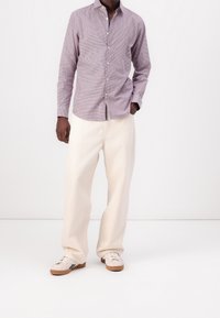 Button-up shirt in purple and white checkered pattern, paired with cream-colored wide-leg trousers and tan sneakers with dark accents.