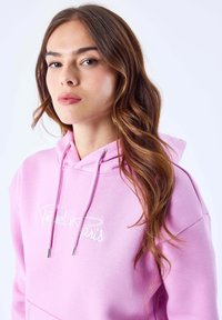 Felpa in cotone rosa con ricamo bianco "Project Paris", con tasca a scomparsa frontale e cordini con punta in metallo.