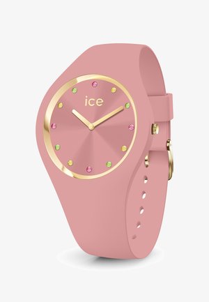 Roze siliconen horloge met een goudkleurige bezel, een ronde wijzerplaat en kleurrijke edelsteen uurmarkeringen. Heeft gouden wijzers en een gespsluiting.