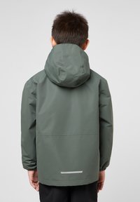 Giacca verde impermeabile con cappuccio, maniche lunghe, polsini elastici e dettagli riflettenti sulla schiena, che presenta una texture liscia e opaca.