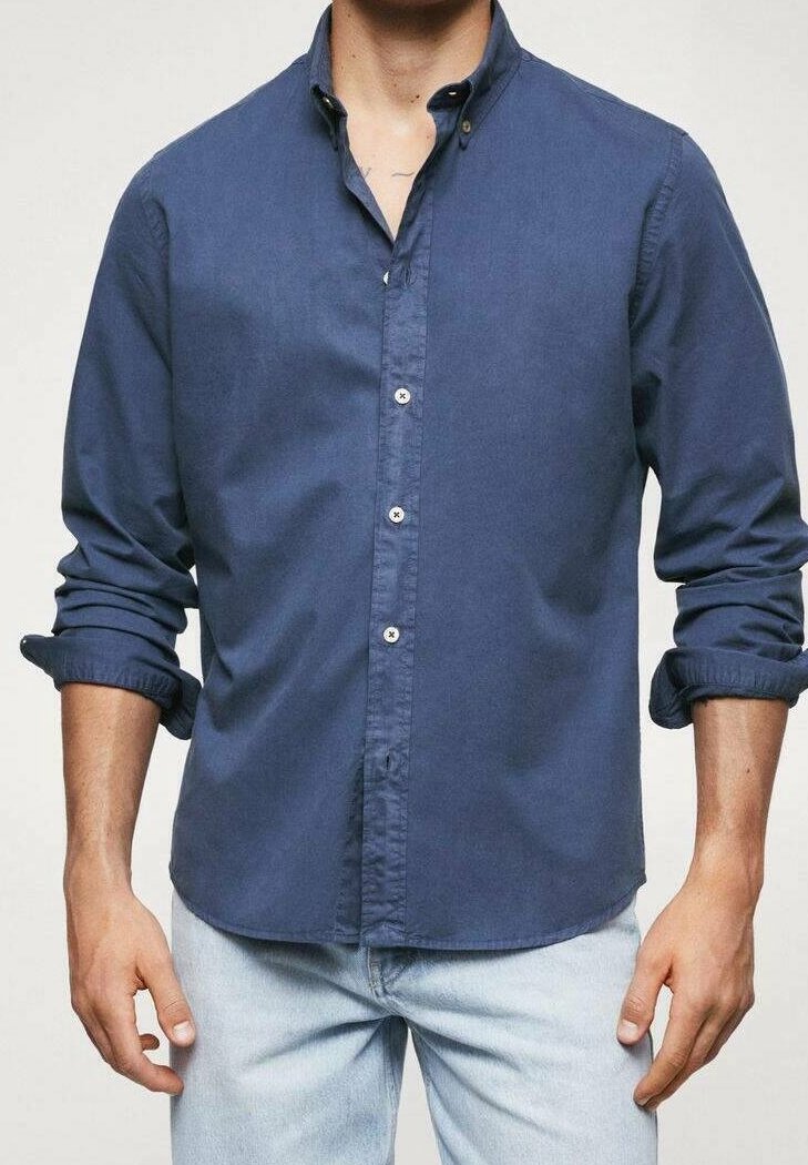 Chemise boutonnée bleu marine en tissu doux et léger, avec un col pointu, des manches retroussables et des boutons blancs classiques.