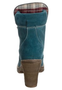 Zelené semišové kotníkové boty s textured hnědým podpatkem, s kostkovanou látkovou podšívkou a kontrastním bílým prošíváním podél švů.