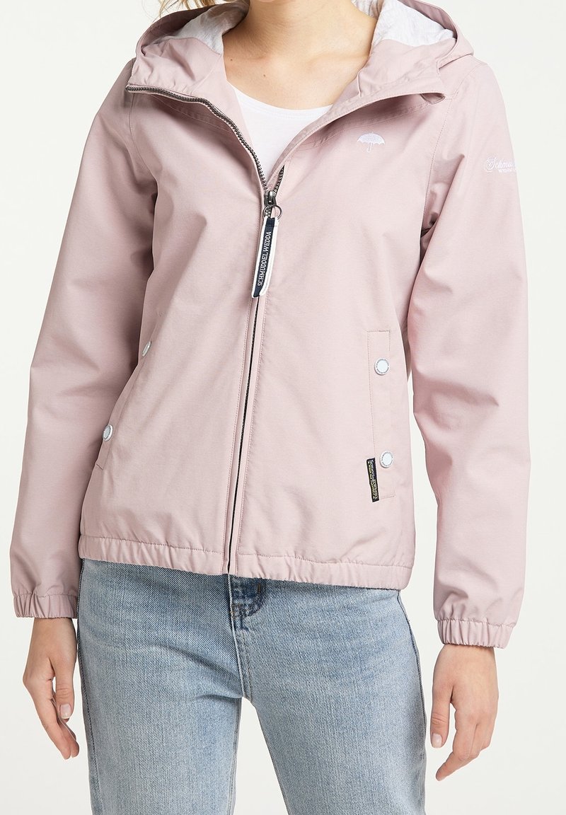 Veste étanche rose clair avec capuche, fermeture éclair avant, poignets élastiques et poches à boutons-pression. Présente des accents de logo et une texture lisse.