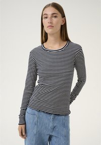 Maglia a maniche lunghe realizzata in tessuto a coste, con righe orizzontali blu navy e bianche, dotata di scollo rotondo e forma aderente.