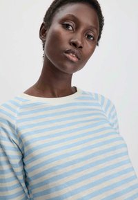 Vaaleansininen ja kerma-valkoinen raidoitettu collegepaita, jossa on pyöreä kaula-aukko ja raglan-hihat, valmistettu pehmeästä puuvillakankaasta. Tasainen pinta.