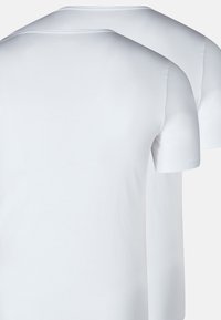 To ensfarvede hvide T-shirts med kort ærme og rund hals, der overlapper hinanden mod en neutral baggrund.