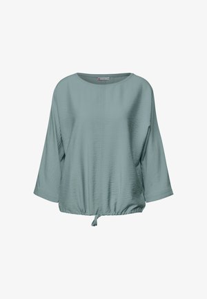 Lichtblauwe blouse met driekwart mouwen, ronde halslijn en een geraffineerde onderrand met een strik; heeft een textuurstof voor extra detail.