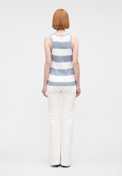 Haut sans manches rayé bleu et blanc, fabriqué dans un tissu doux. Associé à un pantalon flare blanc, présenté de dos.