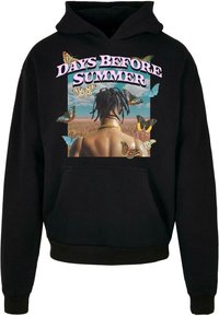 Sort hoodie med et centralt grafik, der viser en persons ryg omringet af sommerfugle, omkranset af teksten "DAYS BEFORE SUMMER" i pink.