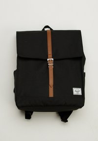 Czarny plecak z tkaniny z klapą, brązowym paskiem ze skóry, srebrnymi okuciami i białą metką z logo w dolnym prawym rogu.