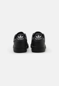 Sorte sneakers med glat læderoverdel, tydeligt hvidt logo på hælen, afrundet tå, polstret krave og struktureret sål for godt greb.