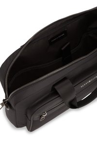 Μαύρη τσάντα από νάιλον με ομαλή υφή και ασημένιο φερμουάρ. Διαθέτει εσωτερικό διαμέρισμα, ρυθμιζόμενο ιμάντα και εξωτερική τσέπη με φερμουάρ.