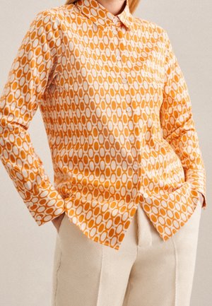 Camicia a righe arancioni e bianchi con un design ovale, maniche lunghe e colletto, abbinata a pantaloni chiari dal tessuto testurizzato.