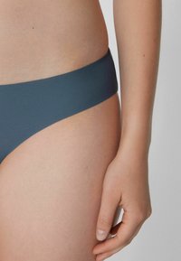 Námořnické modré bikini spodní část vyrobená z hladkého materiálu, s nízkým pasem a minimálním zakrytím, s čistým a jednoduchým vzhledem.