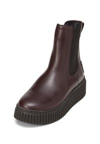 Bottine Chelsea en cuir bordeaux avec panneaux latéraux élastiques, bout rond et semelle en caoutchouc noir texturé. Présente des détails cannelés.