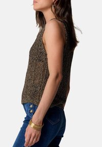 Top in maglia metallica marrone con una vestibilità rilassata, caratterizzato da un collo a giro e spalline sottili, abbinato a jeans in denim blu.