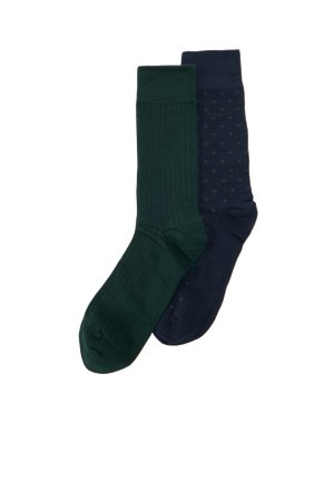 Deux paires de chaussettes montantes vert foncé et bleu marine, dont une paire bleu marine à petits pois verts, présentées sur un fond blanc.