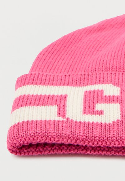 Roze gebreide beanie met een stevige ribbelstructuur, omgeslagen rand en een contrasterend wit logo patroon aan de voorkant.