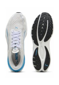 White athletic shoes with mesh upper, blue accents, and purple branding. Features a textured black rubber sole with unique tread patterns.