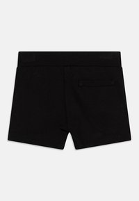 Černé bavlněné šortky s jednoduchým designem, vybavené pasem a jednou zadní kapsou. Hladká textura a zakončené okraje.