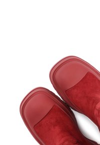 Stivaletti alla caviglia in suede rosso con suola in gomma liscia, punta rotonda e dettagli a pannello discreti. La parte superiore presenta una consistenza morbida e un design senza cuciture.
